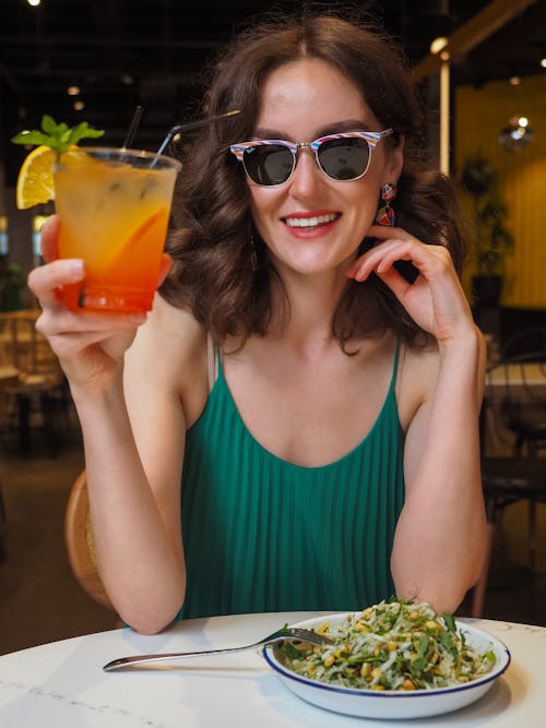 A Woman with Sunglasses Holding a Cocktail Drink