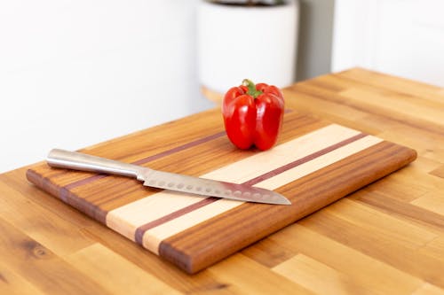 Free A Red Bell Pepper on a Brown Wooden Chopping Board Stock Photo