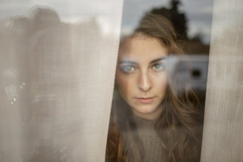 A Woman with a Nose Piercing Behind a Window