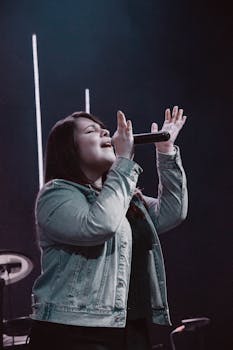 A woman passionately singing into a microphone during a live concert.