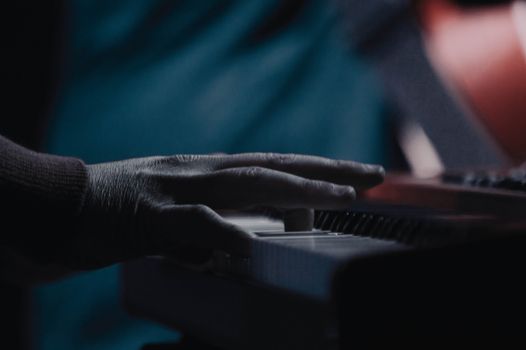 A musician's hand gracefully playing a keyboard in a dimly lit atmosphere, highlighting the art of music.