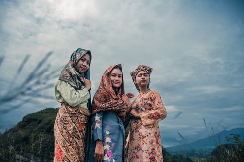 Free Three women pose in traditional clothing against a scenic West Sumatran landscape. Stock Photo