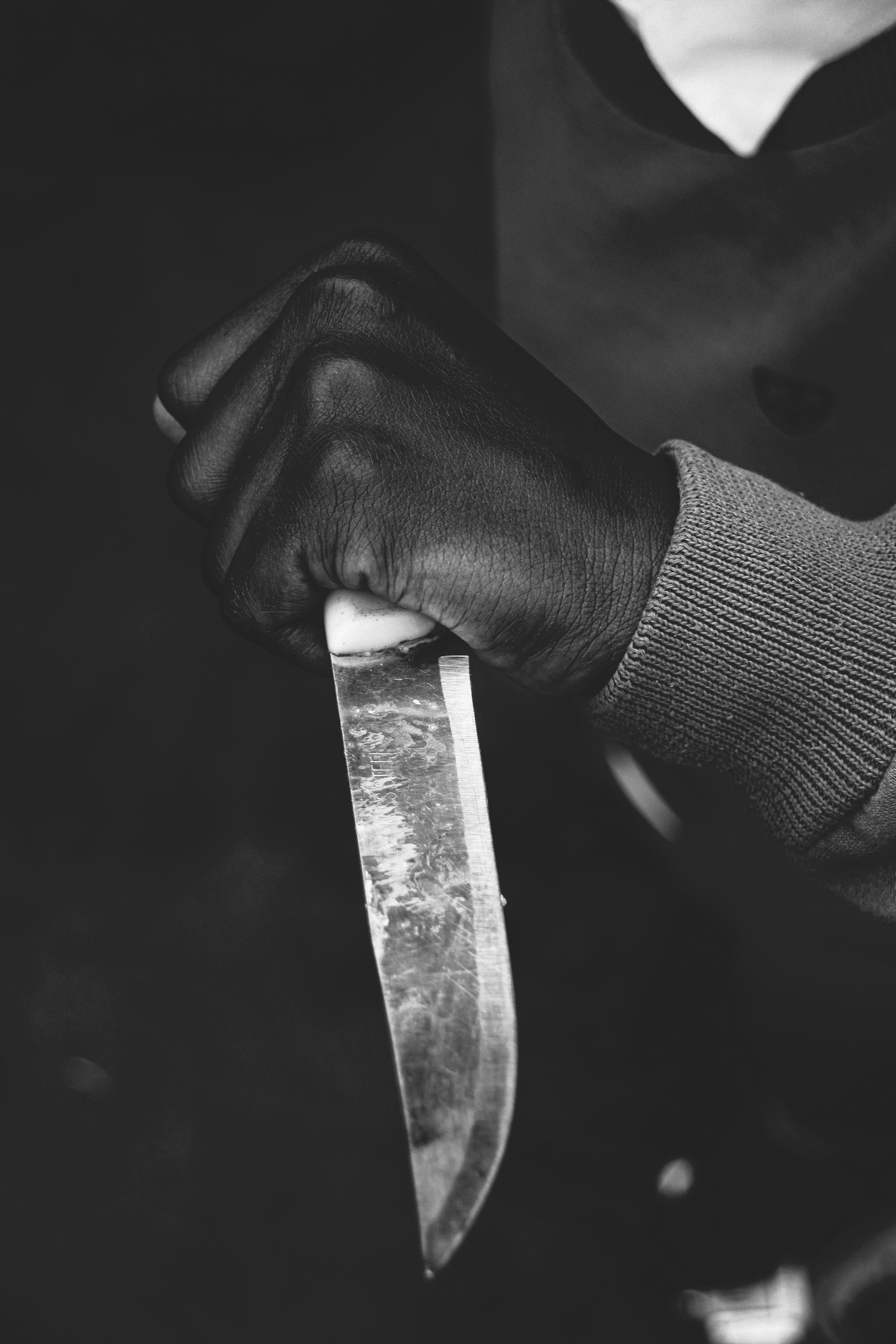 Black and white close-up of a hand gripping a knife, tense and ready