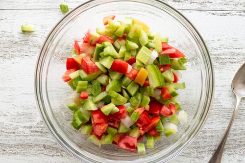 Free Top view of a fresh vegetable salad with cucumbers and tomatoes in a glass bowl on a table. Stock Photo