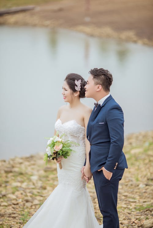 免費 新郎和新娘站在水體附近 圖庫相片