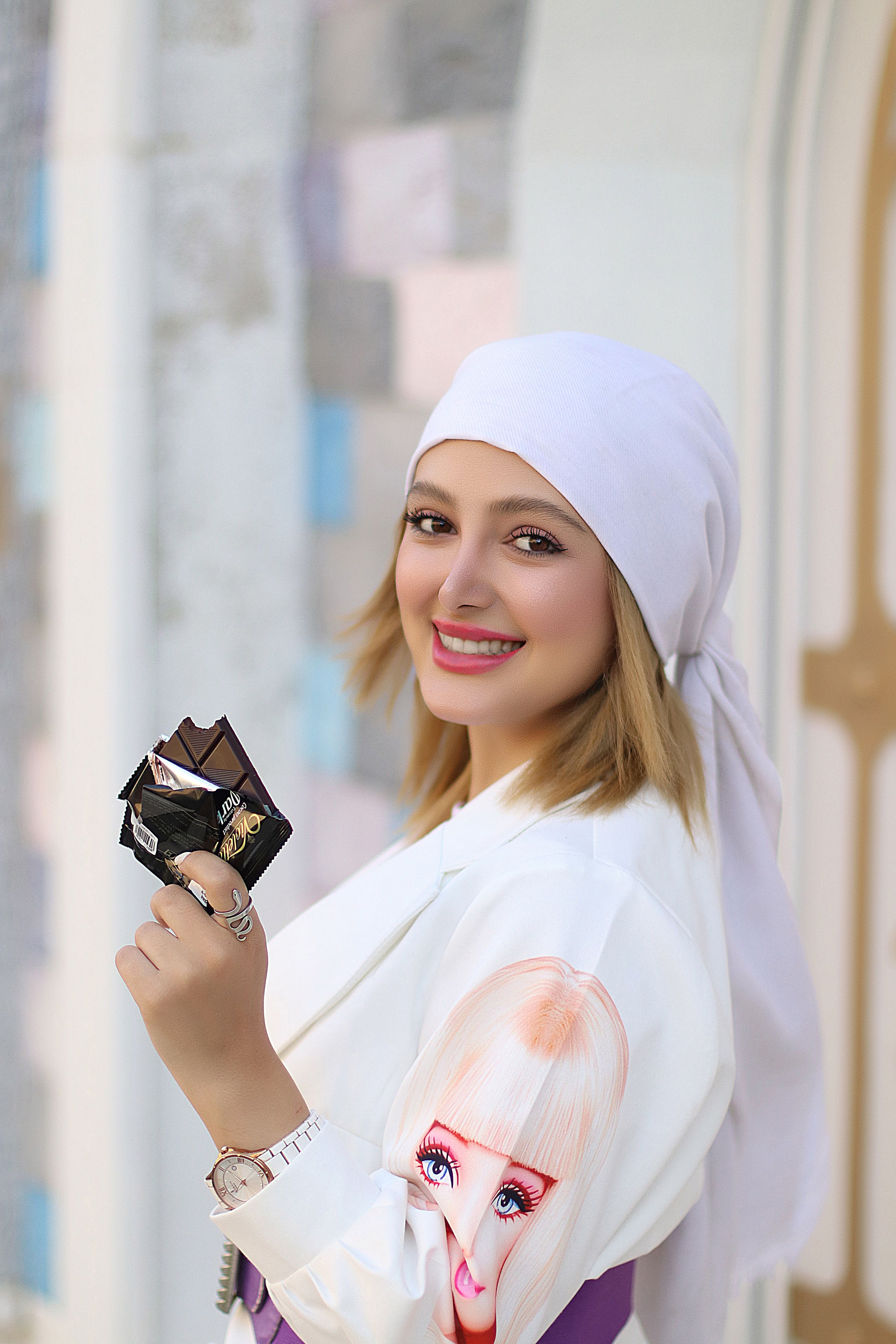 Young woman wearing stylish headscarf and holding a wallet with a vibrant smile.