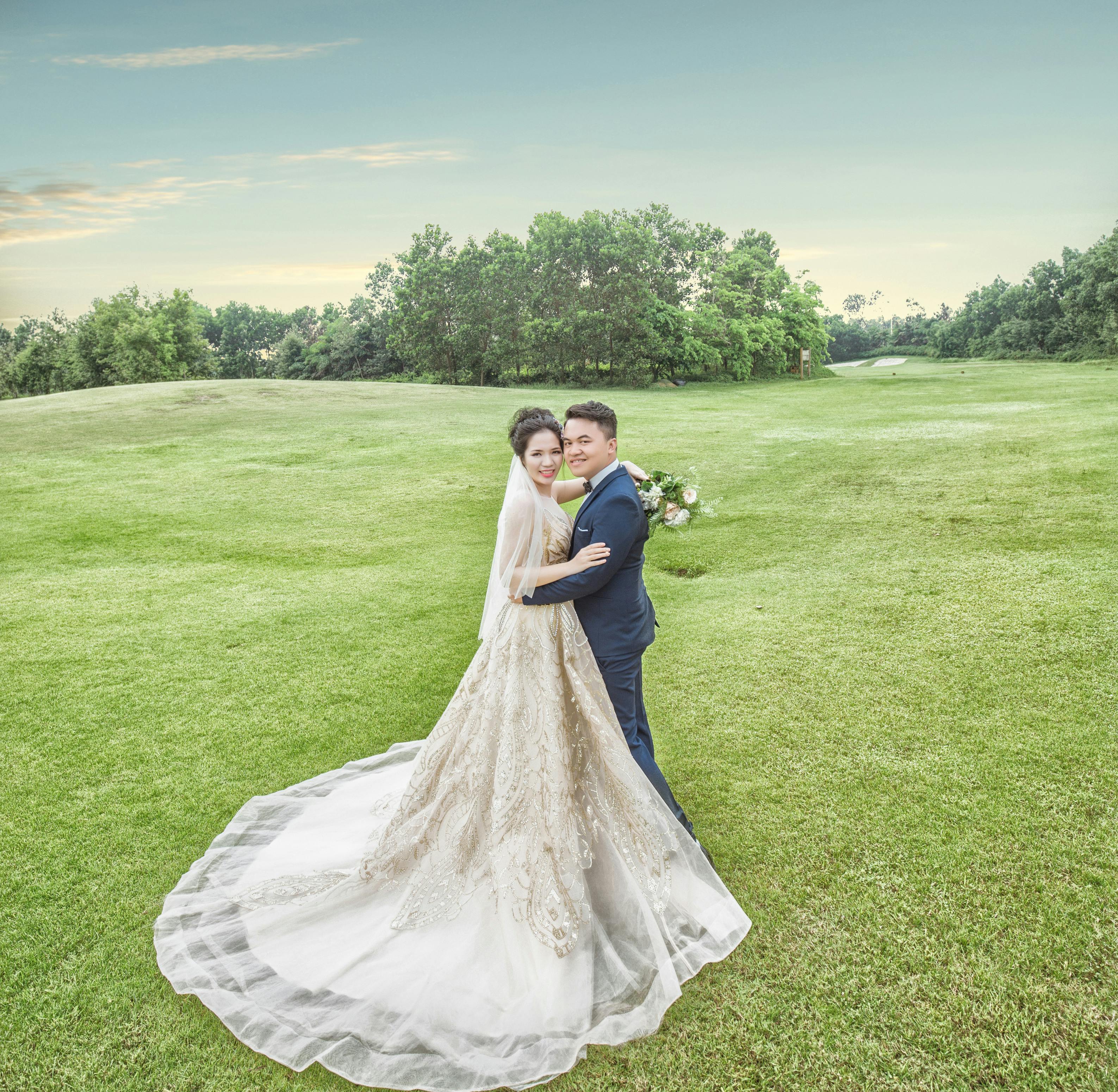 bride and groom standing on green grass field