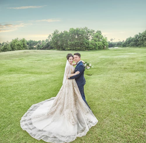 Bride and Groom Standing on Green Grass Field