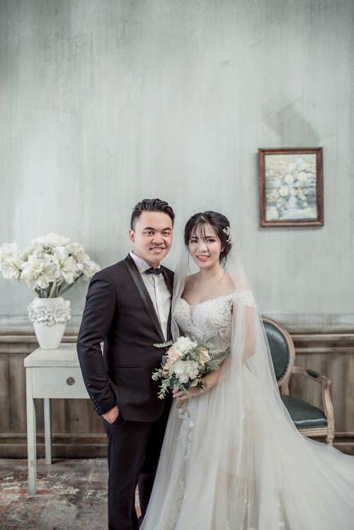 Man and Woman Taking Wedding Photo Inside Gray Concrete House With Wall Arts and Flowers on Vase