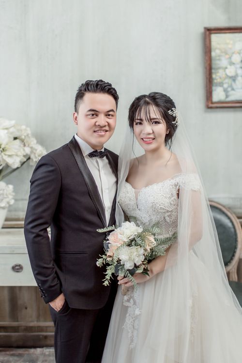 Free Beautiful bride and groom posing indoors with a bouquet, capturing joy and elegance. Stock Photo