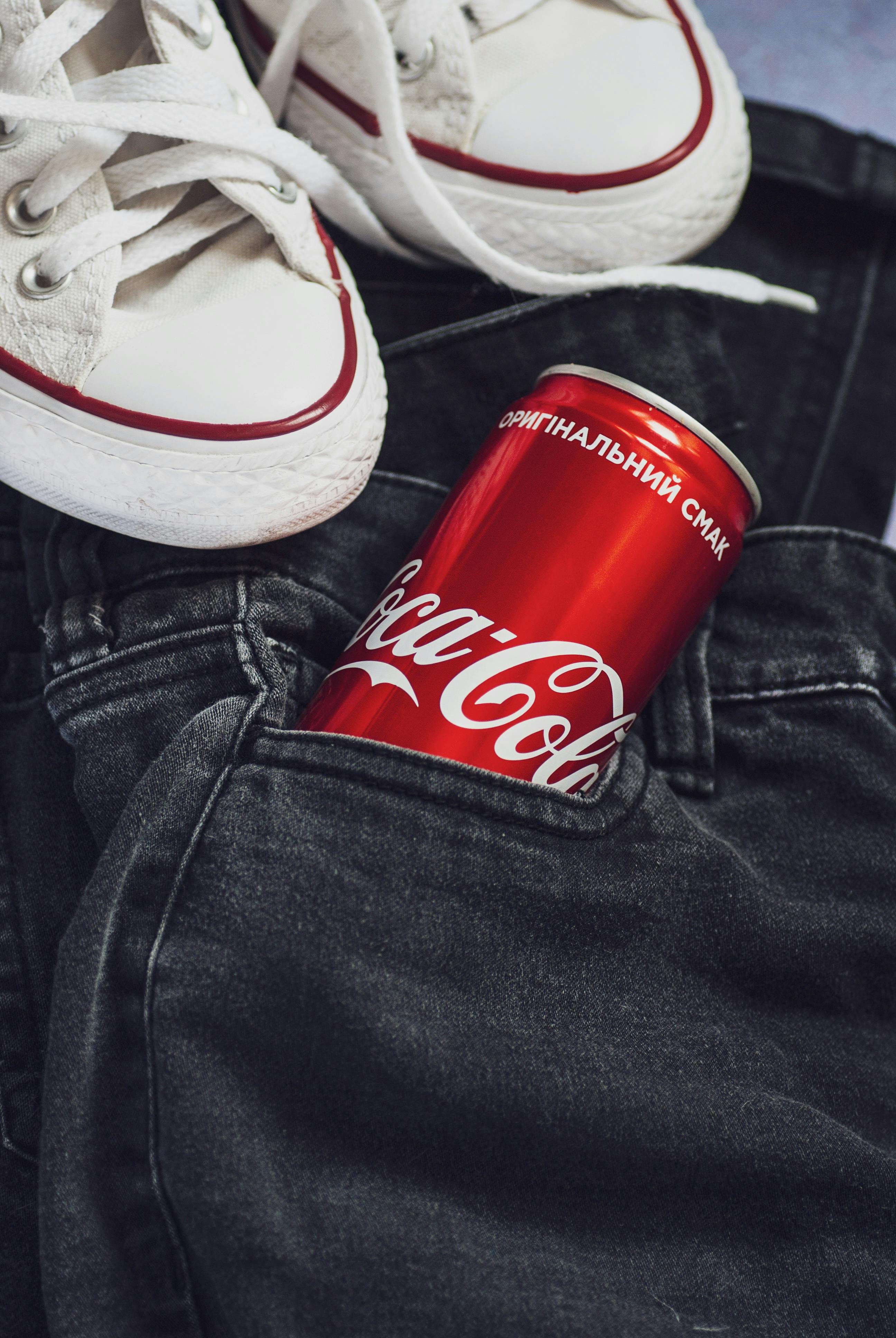 Coca-Cola can in denim jeans with sneakers for trendy urban fashion look.