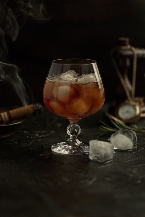 Free A sophisticated still life featuring whiskey with ice and a cigar setting a luxurious tone. Stock Photo