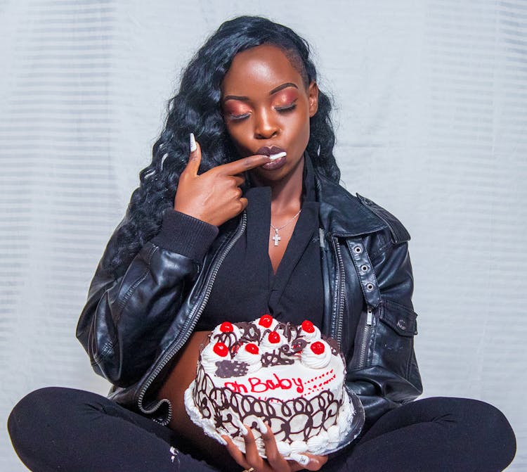 A Woman In Black Leather Jacket Holding A Cake