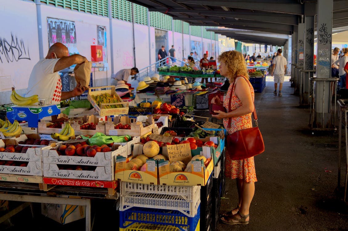 Woman with Red Bag Standing in Front of Fruit Stand