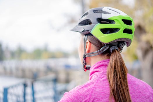 A woman wearing a helmet stands outdoors, viewing an urban landscape.