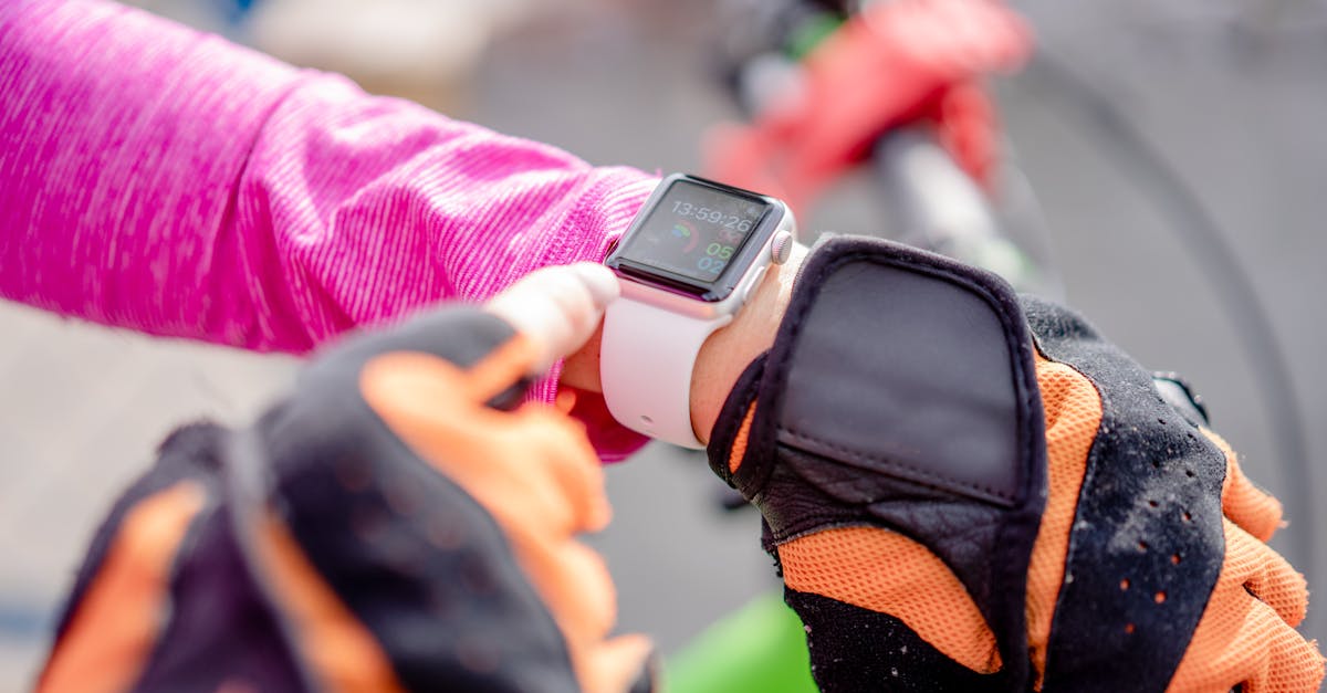 Close-up of a cyclist wearing gloves checking a smartwatch outdoors.