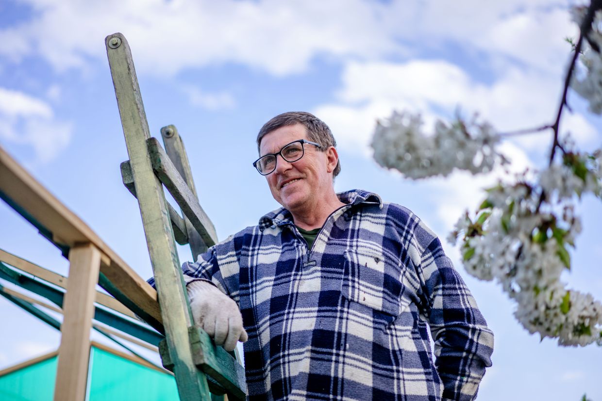 Smiling man with glasses beside a wooden ladder