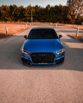 Front view of a blue Audi sports car on a scenic open road, highlighting luxury design.