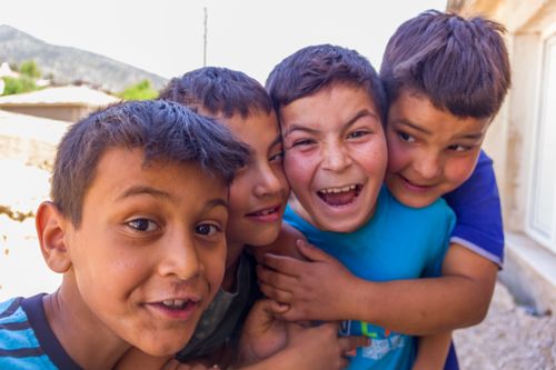 Free Four boys laughing and hugging outside, showcasing friendship and happiness. Stock Photo