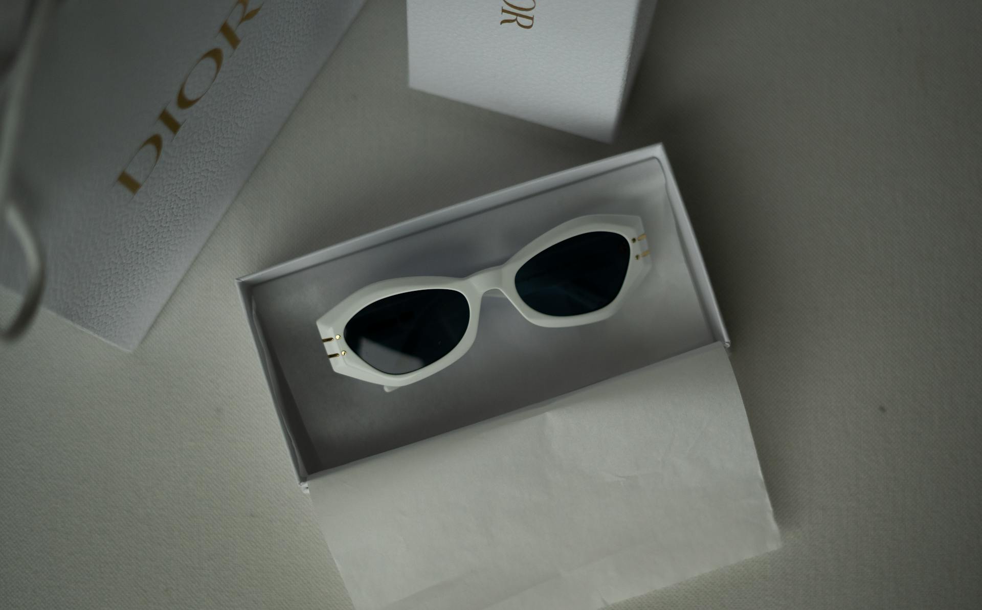 Chic Dior sunglasses in a sleek white frame, displayed in a luxury branded box.