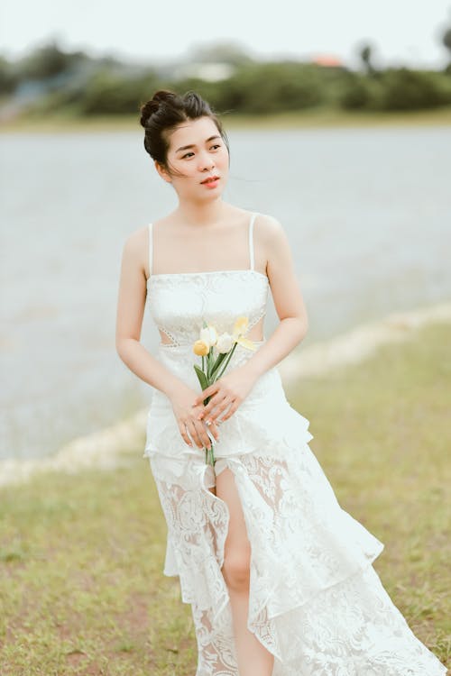 A Woman in White Lace Dress Holding Flowers