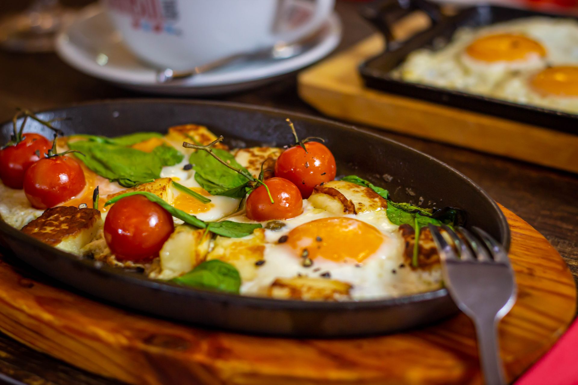 Appetizing Turkish breakfast featuring baked eggs, tomatoes, and fresh ingredients in a skillet.