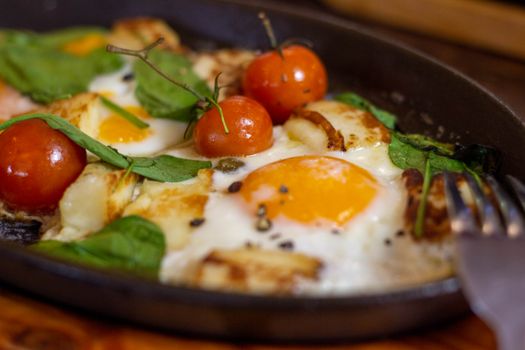 A mouthwatering sunny side up egg dish with tomatoes and spinach, perfect for breakfast.