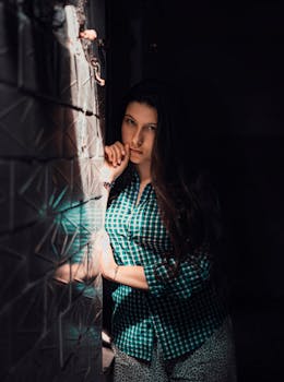 这幅肖像引人注目，描绘了一名女子站在纹理墙壁前，灯光明亮