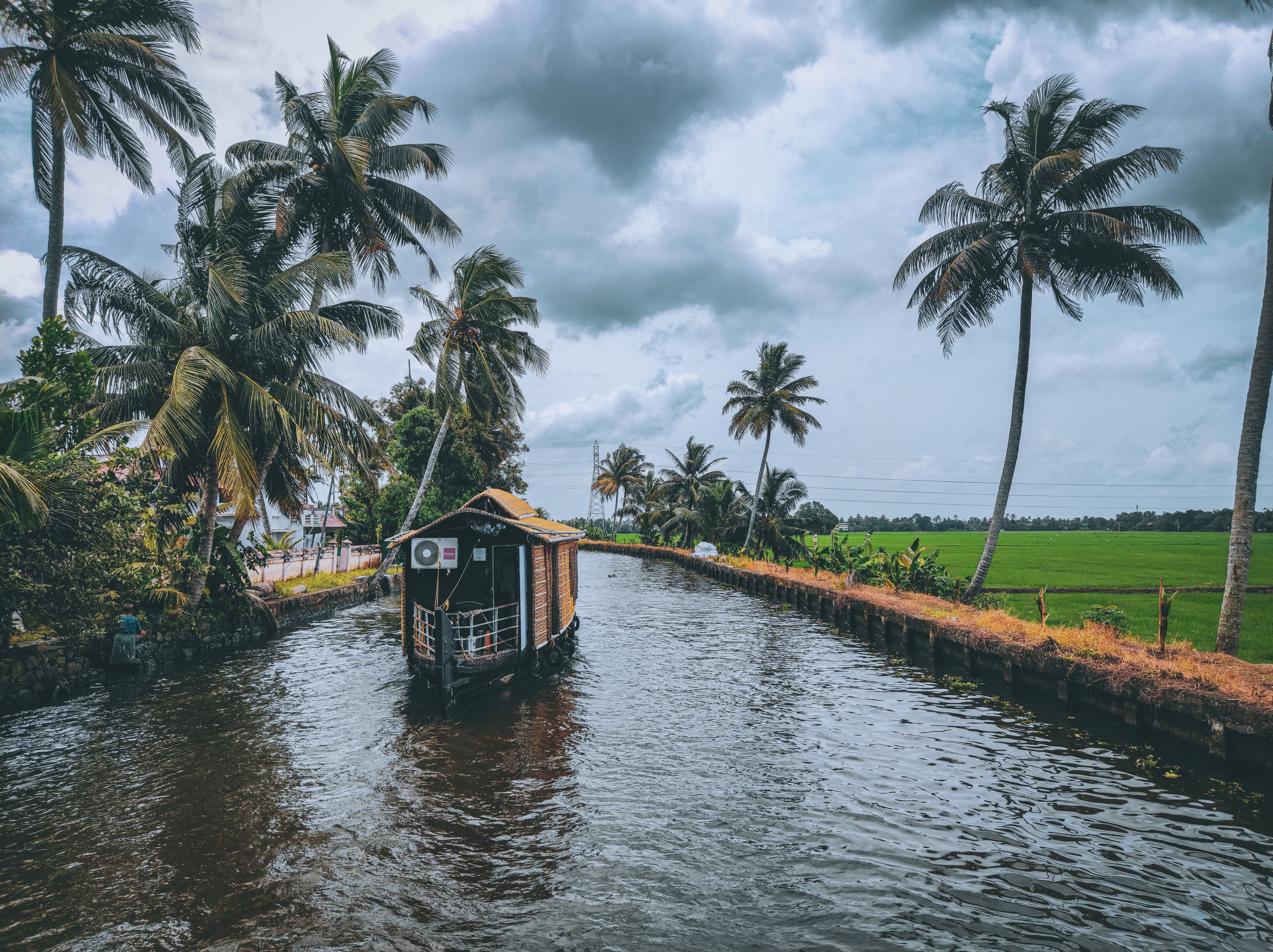 A houseboat on a narrow Kerala backwater canal lined with coconut palms