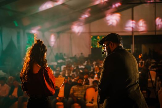 Performers engaging with an audience at a lively indoor event with colorful lighting.