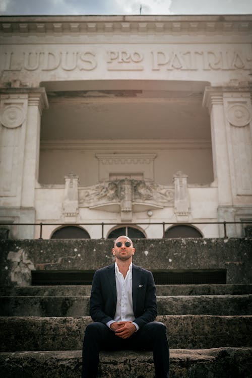 A Man in Black Suit Sitting on Concrete Stairs