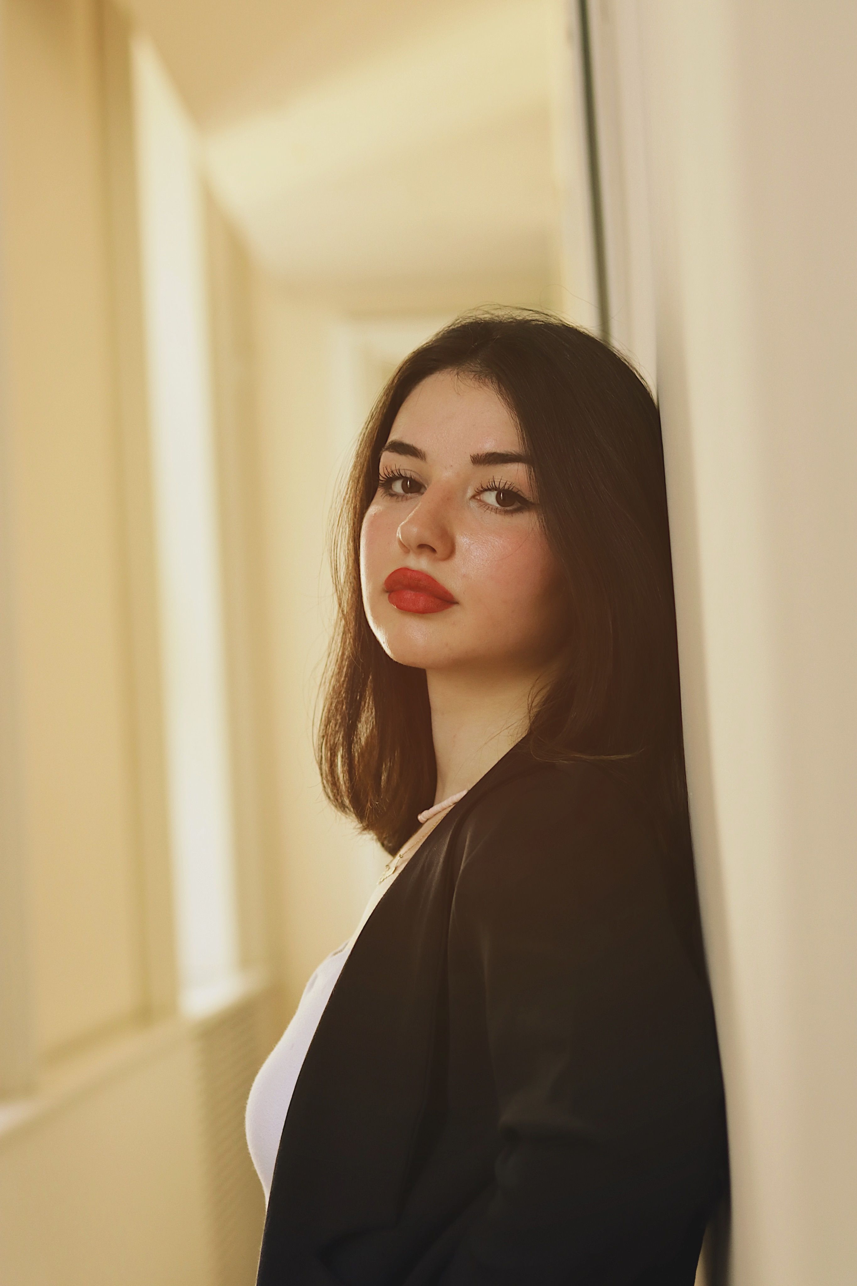 Portrait of a young woman in a black blazer, exuding elegance and style indoors.