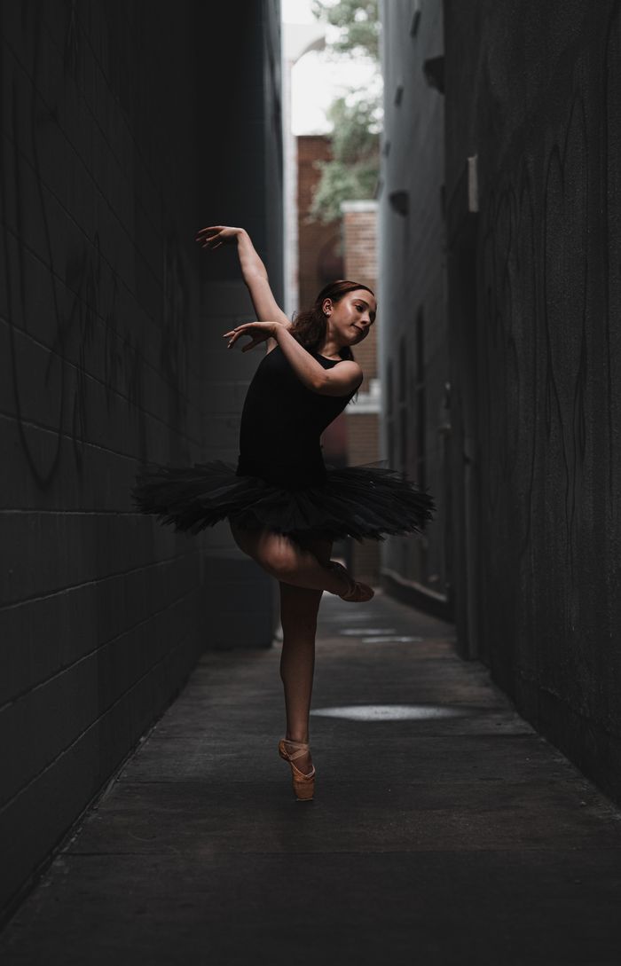 Ballerina in a black tutu posing in the city at dusk