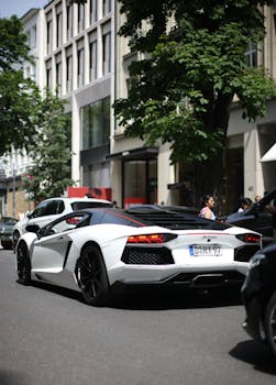 A sleek white sports car parked on a bustling urban street with modern buildings.