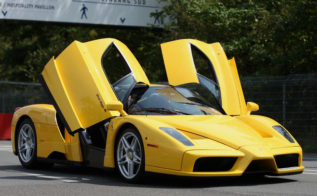 a sleek yellow luxury sports car with scissor doors open on a sunny da