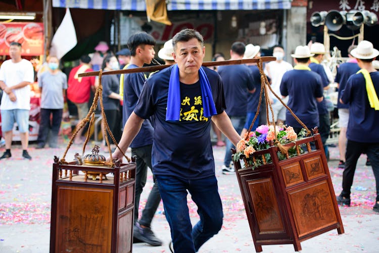 Man Carrying Boxes With Flowers And Incense