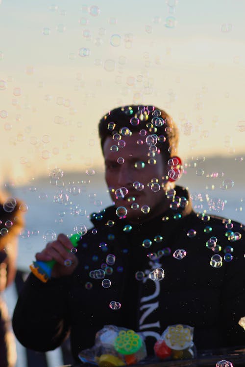Man in Black Jacket Blowing Bubbles
