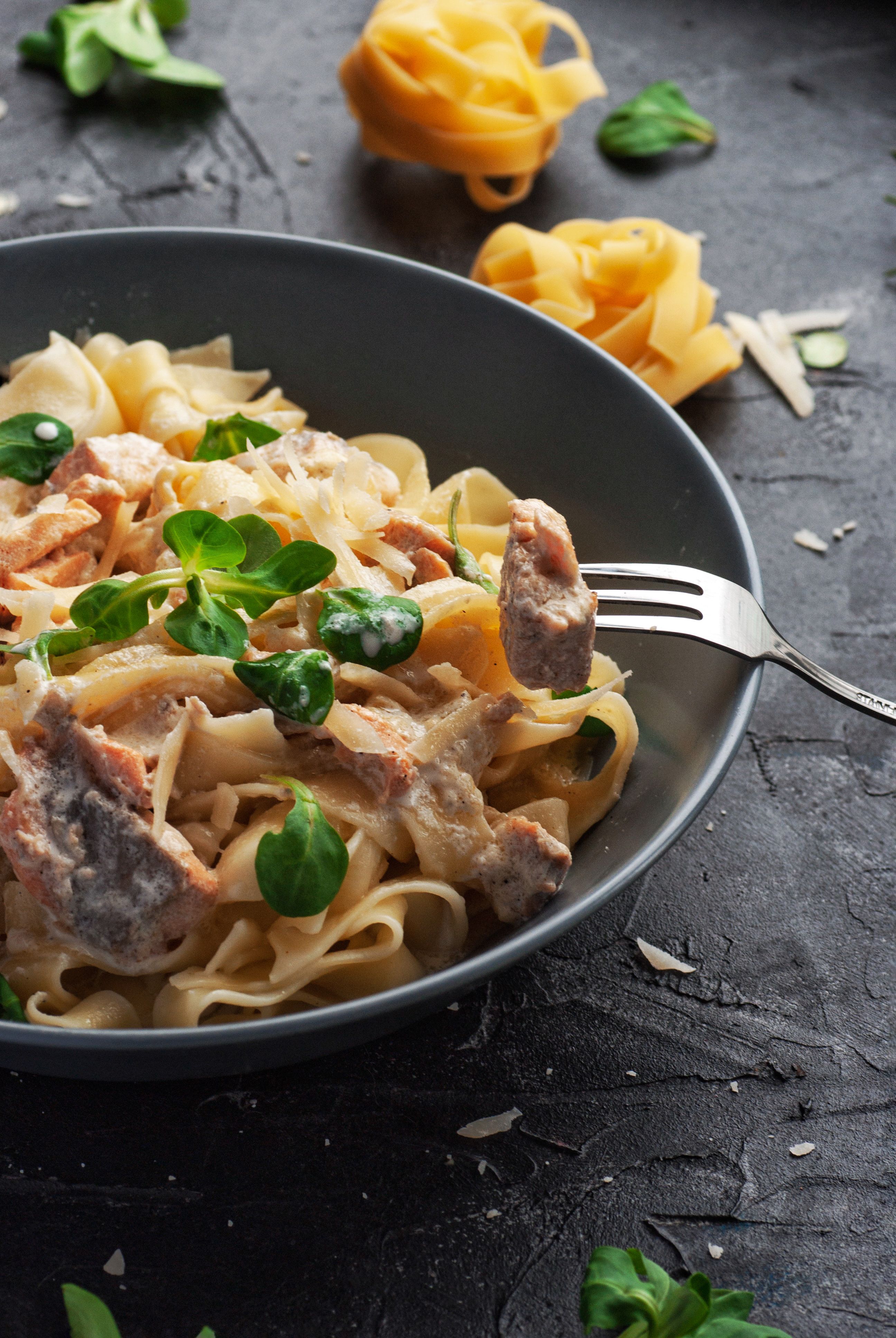 Delicious creamy tagliatelle pasta topped with fresh herbs and served in a stylish bowl.