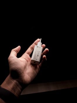 A close-up shot of a person's hand holding a USB wall charger against a dark background.