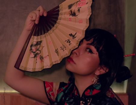 Stylish portrait of a woman with a traditional fan, indoors, showcasing cultural elegance.