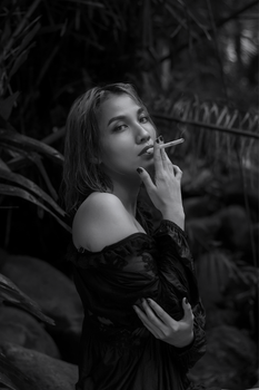 A dramatic black-and-white portrait of a woman smoking, evoking a mysterious mood.