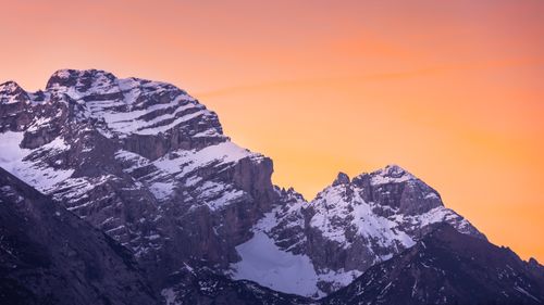 Free Breathtaking view of snow-capped mountains under an orange sunset sky at Madonna di Campiglio, Italy. Stock Photo