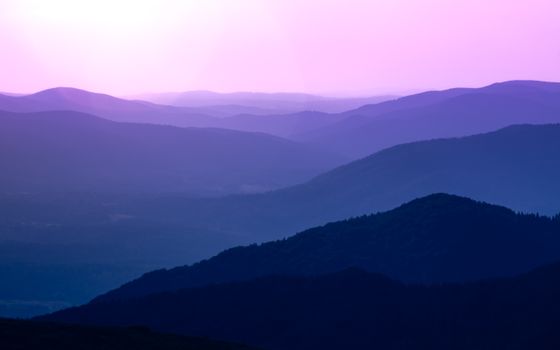 Purple and pink-hued mountain silhouettes during twilight in Podkarpackie Voivodeship, Poland.