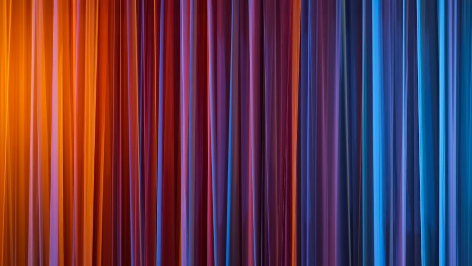 A vivid abstract background featuring vertical gradient lines in blue, purple, and orange hues.