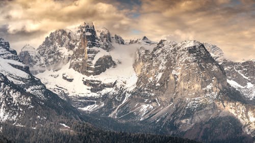 An Aerial Photography of a Snow Covered Mountain Under the Cloudy Sky