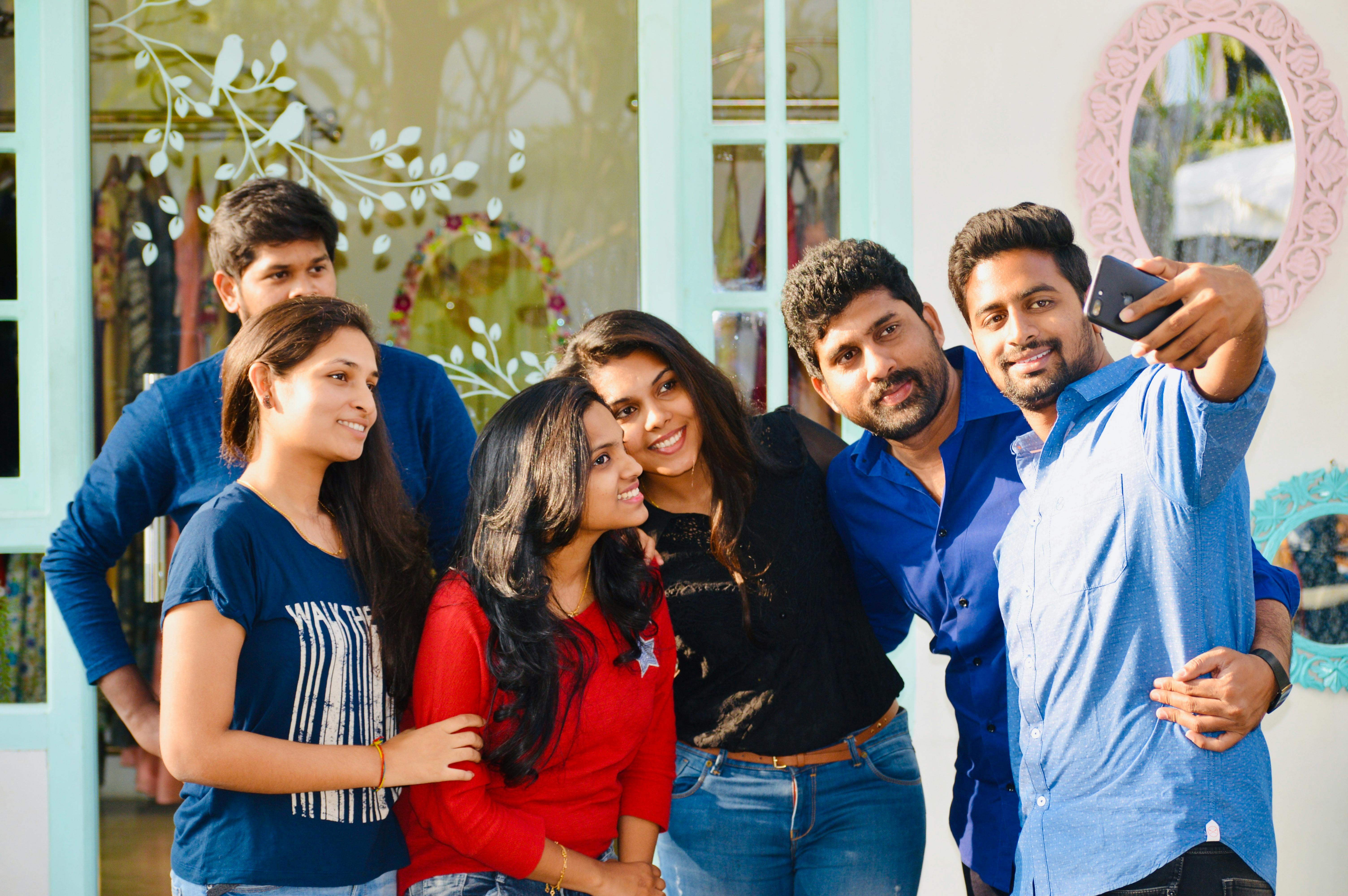 Group Of Friends Excluding One Person From A Gathering, Showing Social Media Posts With The Excluded Friend Looking Upset