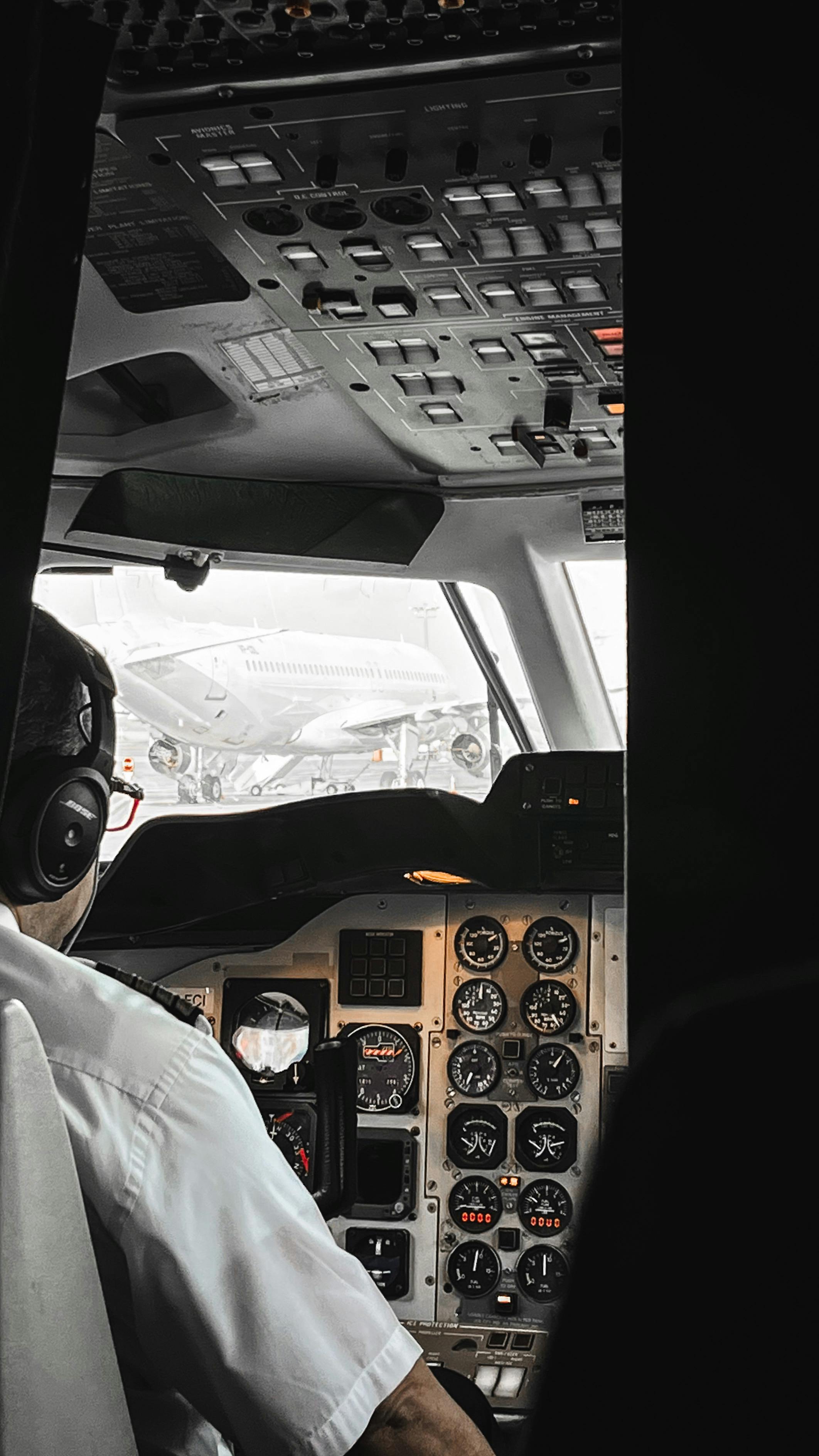View of a pilot in the airplane cockpit with various flight controls and instruments.