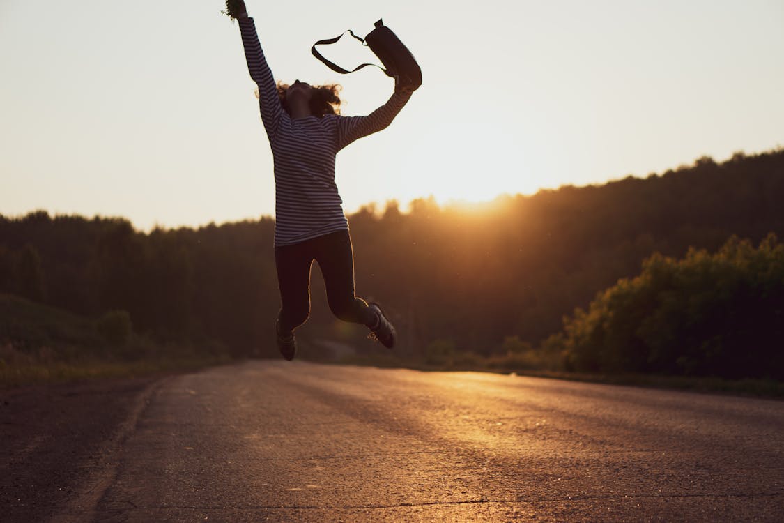 Free Woman Jumped on Gray Asphalt Road Stock Photo