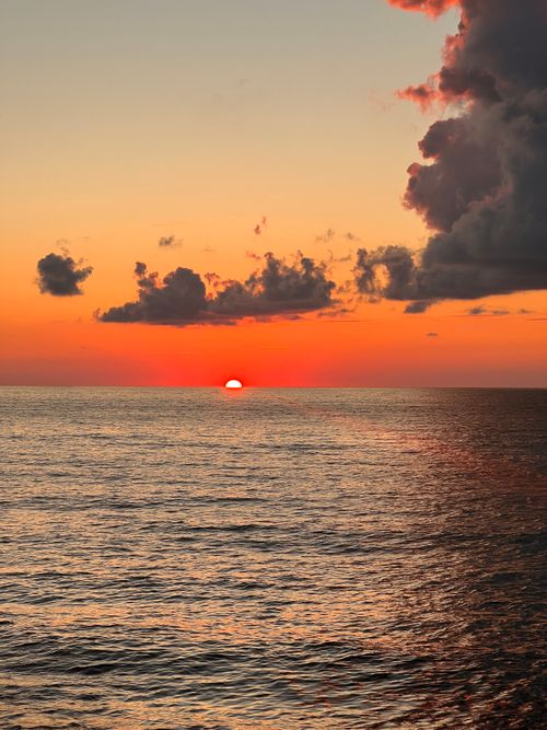 Free Beautiful ocean sunset with vibrant colors and dramatic cloud formations. Stock Photo