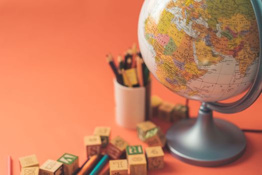 A globe and alphabet blocks create an educational setup on an orange surface, ideal for learning themes.